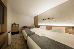 a hotel room with two beds and a television at Shizutetsu Hotel Prezio Kyoto Shijo in Kyoto