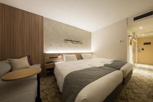a hotel room with a large bed and a chair at Shizutetsu Hotel Prezio Kyoto Shijo in Kyoto