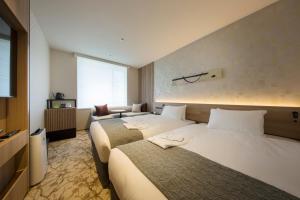 a hotel room with two beds and a television at Shizutetsu Hotel Prezio Kyoto Shijo in Kyoto
