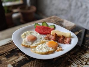 a plate of food with eggs bacon and fruit on a table at DIONIS Rooms & Apartments in Prilep