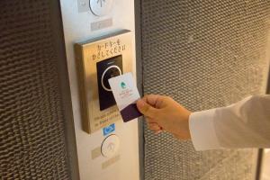 a person is holding a card in a vending machine at Shizutetsu Hotel Prezio Kyoto Shijo in Kyoto
