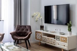 a living room with a chair and a tv on a wall at Apartamentos Turísticos Moret 11 - 1C in Cáceres