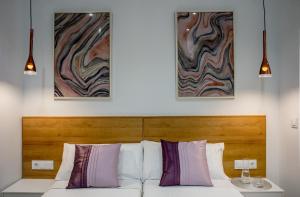 a white bed with two paintings on the wall at Apartamentos Turísticos Moret 11 - 1C in Cáceres