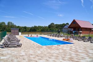 een zwembad met ligstoelen en een huis bij Rancho Zapotoczny in Łagów
