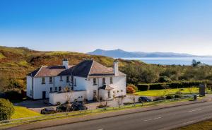 a white house on the side of a road at Toravaig House Hotel in Teangue