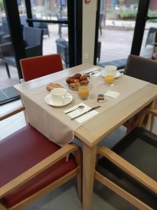 ピュイルボローにあるRSS DOMITYS Les Vignes Pourpresのドーナツ一皿とオレンジジュース二杯のテーブル