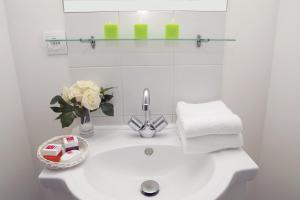 a white bathroom sink with towels and a vase of flowers at Séjours & Affaires Pantin Charles De Gaulle in Pantin +7 photos