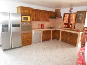 eine Küche mit Holzschränken und einem Kühlschrank aus Edelstahl in der Unterkunft CHEZ JACQUELIN ET DORLYS in Saint-André