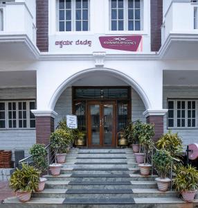 an entrance to a building with potted plants on the stairs at Aishwarya Residency in Mysore