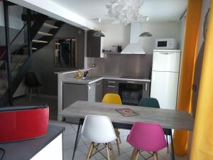 a kitchen with a table and colorful chairs at Agréable duplex au centre ville de Brioude in Brioude