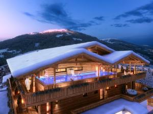 una baita di tronchi nella neve di notte di Boutiquehotel die Alpbacherin ad Alpbach