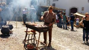 a man cooking meat on a grill on a street at BB Silvercoast Casa das Flores in Santa Catarina