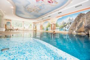 a swimming pool in a hotel with a painting on the ceiling at Wellness Hotel Post in Solda