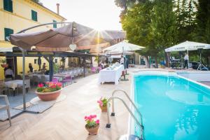 a swimming pool with tables and umbrellas and a restaurant at Tenuta Villa Colle Sereno in Montemarciano