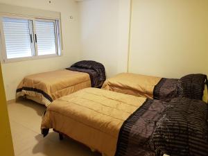 a room with three beds and a window at Departamenos Llanos in Termas de Río Hondo