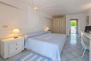 
a bedroom with a bed and a dresser at Club Hotel Baja Sardinia in Baja Sardinia
