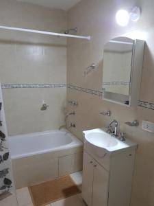 a bathroom with a tub and a sink and a bath tub at Departamenos Llanos in Termas de Río Hondo