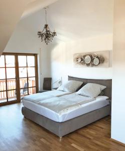 a bedroom with a large bed and a chandelier at Ferienwohnungen Thum in Rosenheim