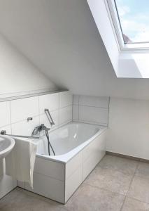 ein weißes Badezimmer mit einer Badewanne und einem Waschbecken in der Unterkunft Ferienwohnungen Thum in Rosenheim