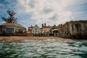 un cartel en una playa al lado de una casa en The George Hotel and Beach Club en Yarmouth