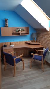 ウージュホロドにあるGuest House Uzhgorodの青い壁の客室で、椅子2脚とテーブルが備わります。