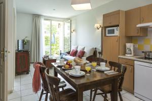 a kitchen and living room with a table and chairs at Résidence Odalys Le Domaine des Rois in Bergheim