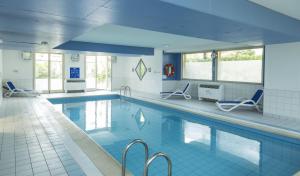 貝格海姆的住宿－Résidence Odalys Le Domaine des Rois，大楼内带蓝色椅子的大型游泳池