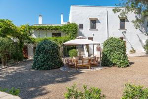 a table and chairs under an umbrella in front of a building at Masseria Santo Stefano Relais&Charming House in Conversano