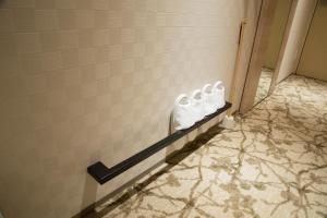a tiled bathroom with three white towels on a wall at Shizutetsu Hotel Prezio Kyoto Shijo in Kyoto
