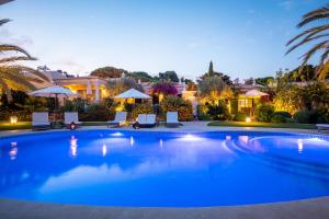 a large pool with chairs and umbrellas in a yard at Vila Balaia - Luxury Boutique Villas in Albufeira