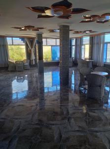 una hall con pavimento in pietra, tavoli e sedie di Bio Palace Hotel a Tinerhir