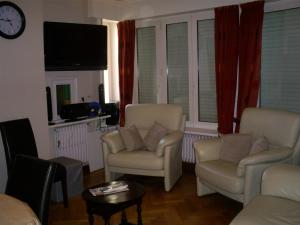 a living room with two chairs and a tv at residentie leopold app 21 in Blankenberge