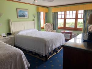 a bedroom with two beds and a chair and windows at Winstead Beach Resort in Harwich Port
