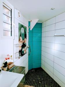 bagno con doccia e piastrelle blu di Chalet "BIENVENUE NOUT KAZ" a Saint-Gilles-les Hauts