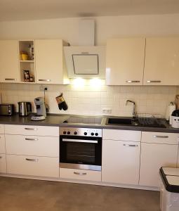 a kitchen with white cabinets and a stove top oven at Sylvias Ranch in Gerstungen
