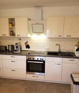 uma cozinha com armários brancos e um forno com placa de fogão em Sylvias Ranch em Gerstungen