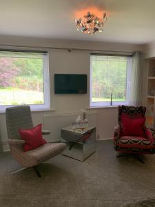 a living room with two chairs and a table and a chandelier at Invercreran Lodge Luxury Bed & Breakfast in Appin