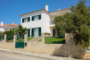 a white house with a stone wall and a fence at Villa Terra Da Eira in Mafra