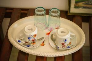 une table avec deux tasses et soucoupes sur une assiette dans l'établissement Snuggle Cottage, à Ella