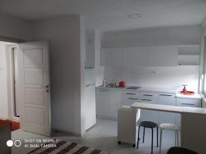 a kitchen with white cabinets and a table and stools at Septemvri 7 in Kavadarci