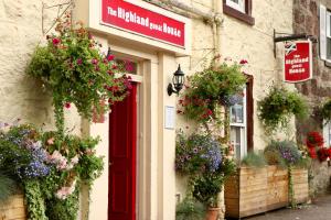 a building with flower baskets and a red door at Highland House Callander in Callander