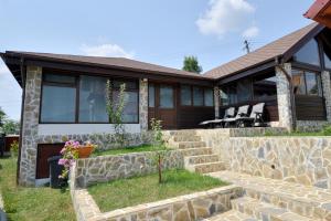 a home with a stone retaining wall and a house at Foisorul Din Poveste in Şerbăneşti