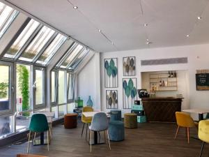a room with chairs and tables and windows at Arthotel ANA Eden in Karlsruhe