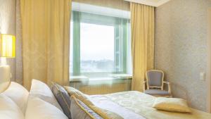 1 dormitorio con cama, ventana y silla en Moscow Hotel, en San Petersburgo