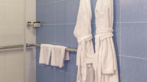 ein Badezimmer mit weißen Handtüchern auf einem Kleiderständer in der Unterkunft Moscow Hotel in Sankt Petersburg