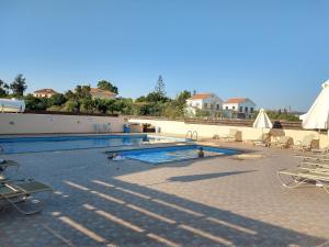 a swimming pool with chairs and umbrellas on a resort at Nissi Golden Sand lovely one bedroom apartment with spacious terrace and free parking in Ayia Napa