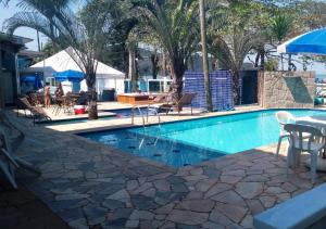 a swimming pool with a table and chairs and palm trees at Pousada Vistazul - Piscina Climatizada - Pé na Areia in Bertioga
