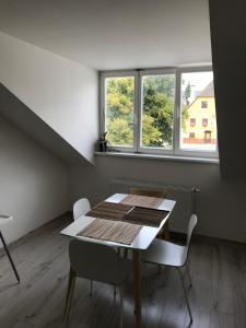 a table and chairs in a room with windows at Apartmán na náměstí in Kašperské Hory