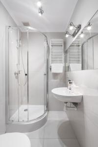ein weißes Bad mit einer Dusche und einem Waschbecken in der Unterkunft Square Apartment by LoftAffair in Krakau