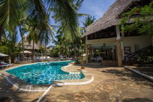a swimming pool next to a resort with palm trees at Aquarius Club in Watamu